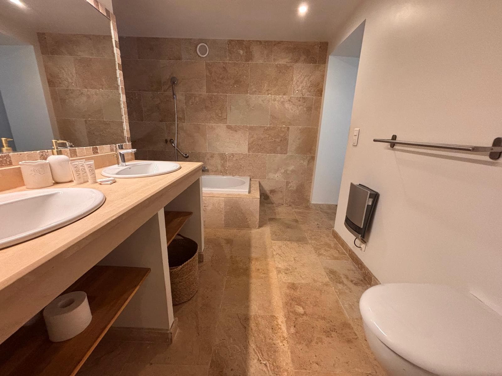 Salle de bain en travertin avec double vasque et baignoire, chambre du rez-de-jardin à Grasse