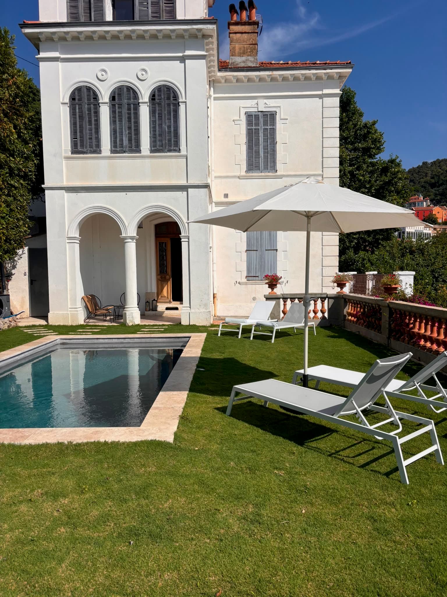 Façade de la villa, piscine et transats sur la pelouse à Grasse
