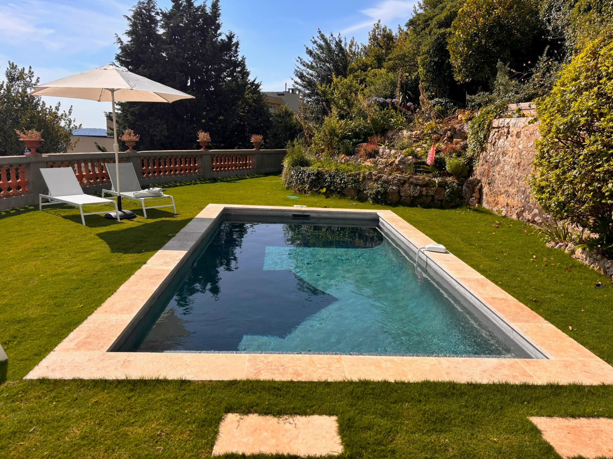 Piscine chauffée de la villa bordée de pelouse et de murets de pierre à Grasse